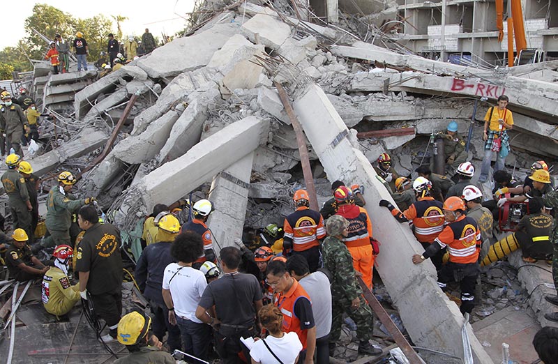Thai rescue workers and soldiers continue their search at the site of a six-story building collapse in Pathum Thani province, just north of Bangkok, Thailand Tuesday, Aug. 12, 2014. The building under construction on the outskirts of Thailand's capital collapsed Monday, killing three workers and trapping at least seven others underneath the rubble, police said. (AP Photo/Apichart Weerawong)